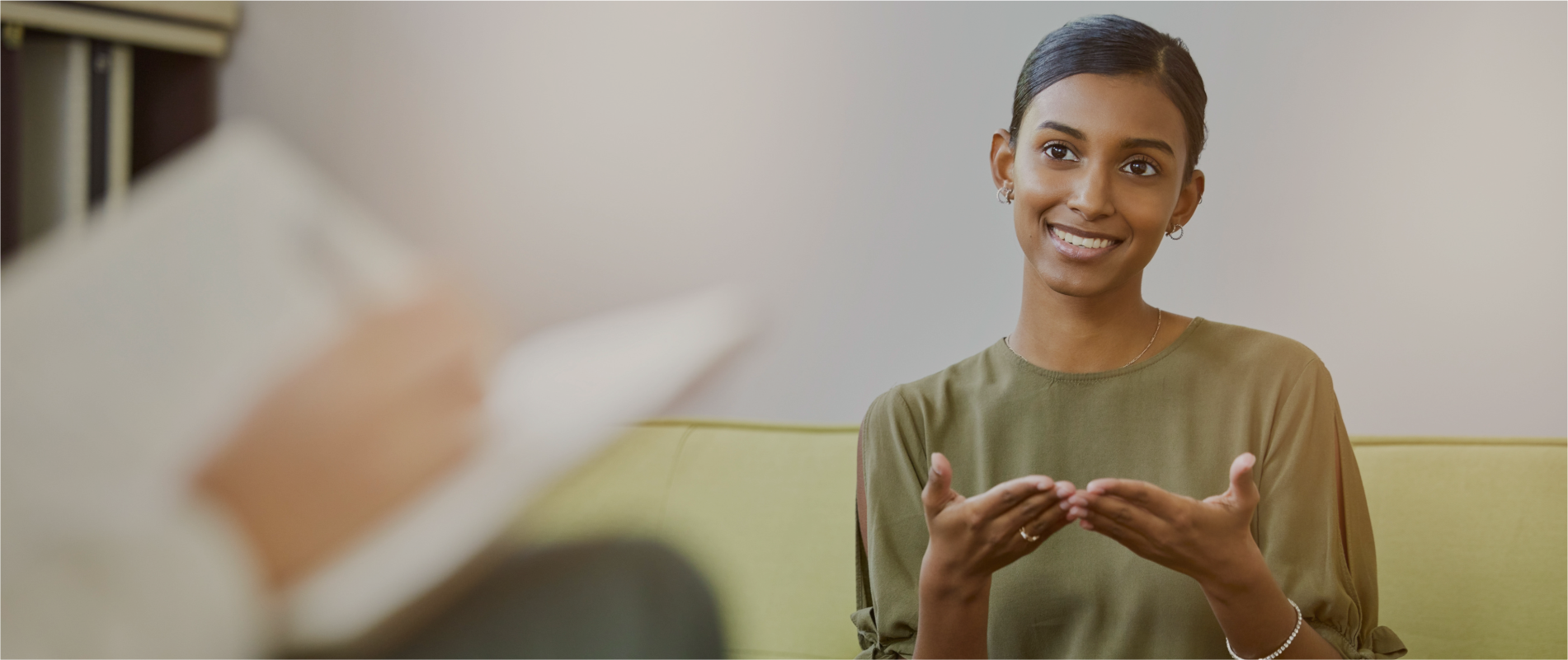 A woman sitting on a couch explaining something to her therapist. Art-based therapy for individuals, couples and families in Melbourne – Book your session with Kathaprana now.