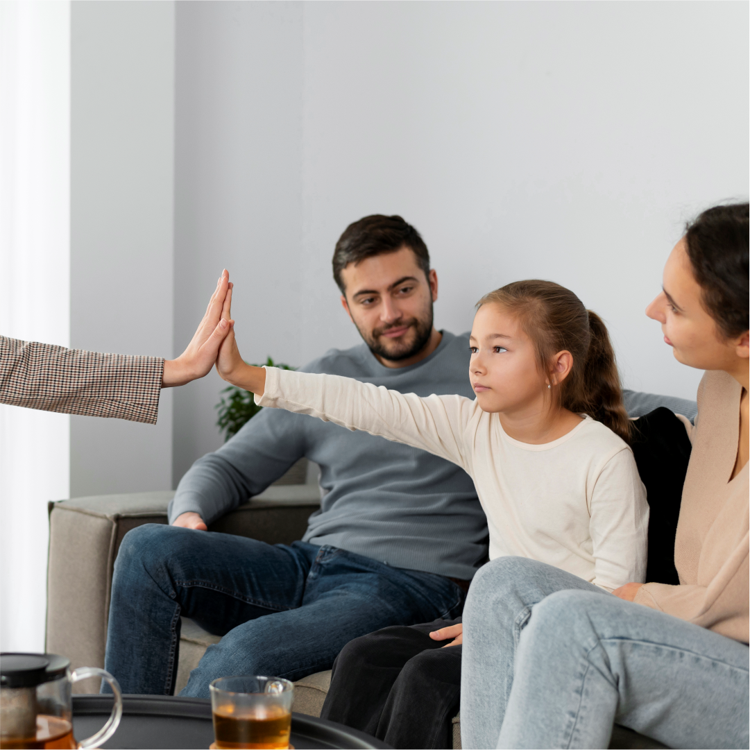 Family sitting on a couch and the child is giving high five to the therapist. South Asian Family therapy center in Melbourne – Opt for healing through movement and mindfulness with Kathaprana.
